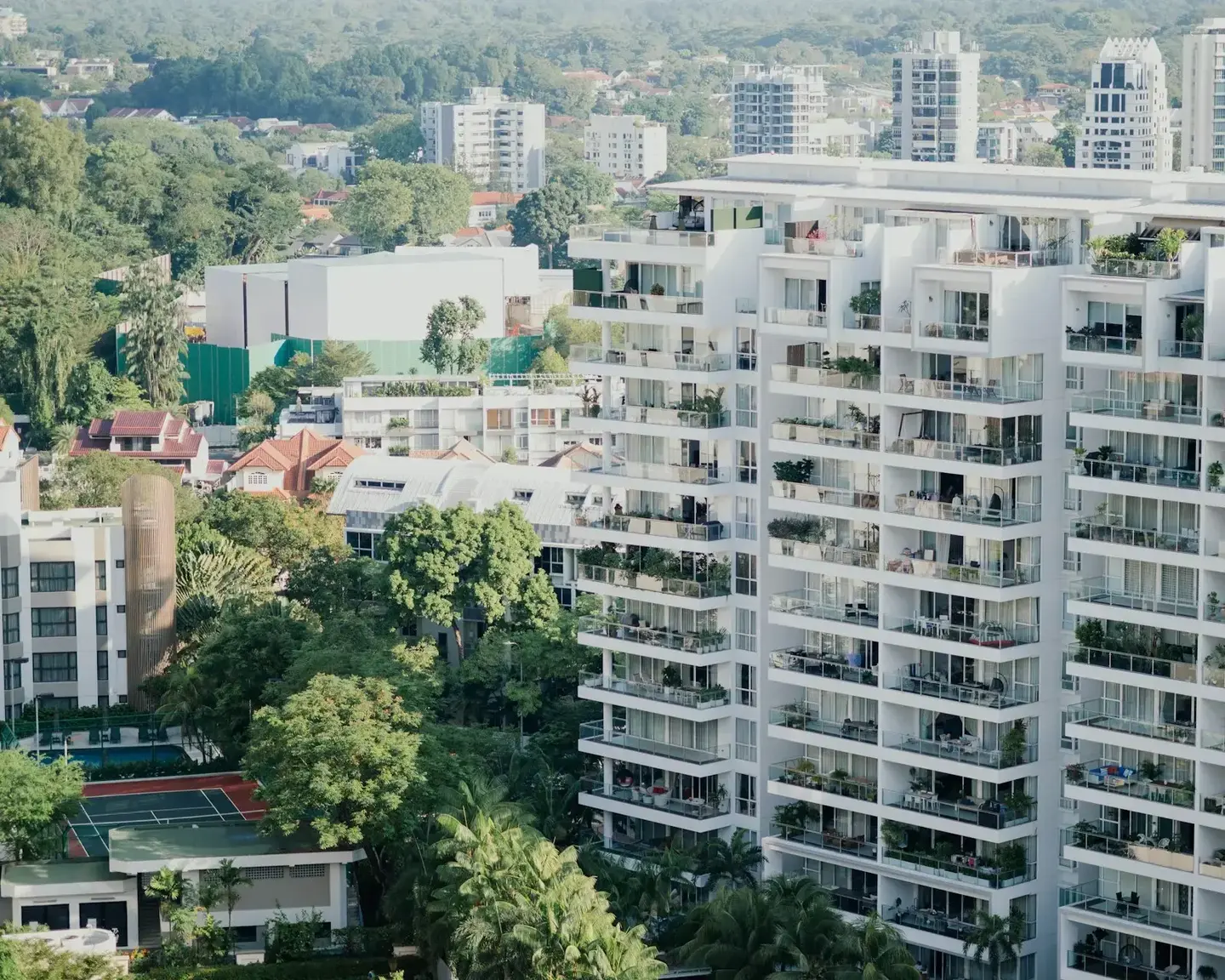 White apartment towers with balconies among tall trees in Kochi